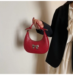 Detail of red crescent bag with woven texture and silver bow metallic hardware