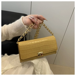 Détail macro du sac jaune motif crocodile avec chaîne dorée et fermoir métallique