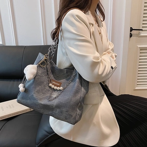 Blue canvas tote bag with pearl chain and plush charm on a fashion model