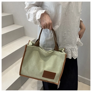 Detail of light green corduroy tote bag with brown straps and vintage leather patch