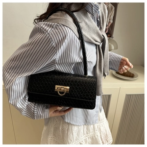 Close-up of black crocodile pattern underarm bag with gold metal buckle on a model