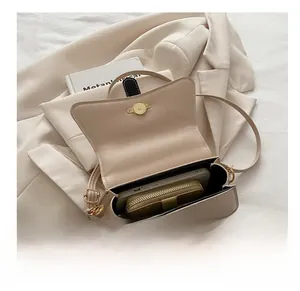 Interior view of minimalist cream shoulder bag showing space for wallet and smartphone