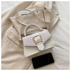 Détail du sac à main blanc avec rabat tissé et boucle dorée sur un tailleur beige