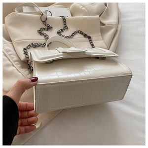Détail de la texture crocodile blanc sur sac à bandoulière avec chaîne en métal