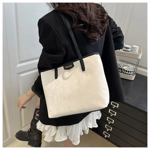 Detailed view of the white tote bag with black straps and fashion label on the leather