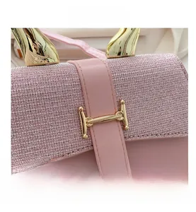 Detailed close-up of pink sequin handbag featuring gold H-clasp and horn-shaped handle