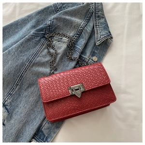 Macro view of red woven leather texture with gunmetal chain and geometric lock detail
