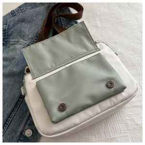 Close-up of color-block nylon crossbody bag with magnetic closures and adjustable strap