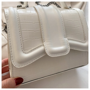 Vue détaillée de la texture crocodile blanche et de la chaîne métallique sur le sac