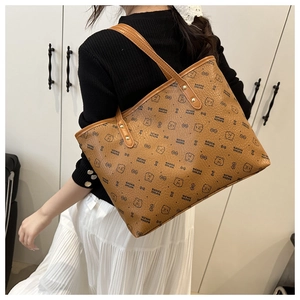 Detail of a brown leather tote bag with bear print patterns and golden metal rivets
