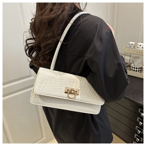 Detail shot of white faux crocodile texture baguette bag with golden metal clasp hardware