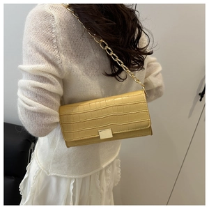Détail du sac à bandoulière jaune clair à motif crocodile avec chaîne dorée chic