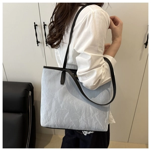 Detail of light blue pleated tote bag with black leather handles and spacious interior