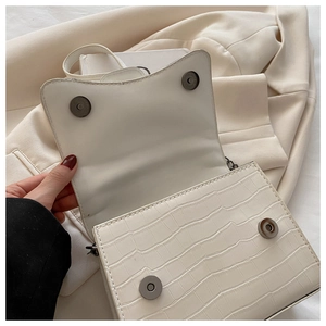 Détail du rabat en cuir blanc à motif crocodile avec double boucle magnétique fermée