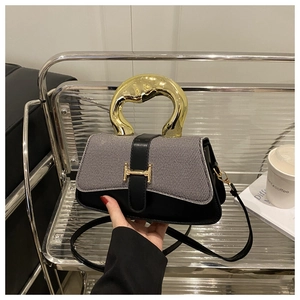 Detailed macro view of an elegant black leather and grey tweed box bag with golden H clasp