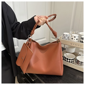 Close-up of caramel brown leather tote bag set with unique knotted handle and inner pouch
