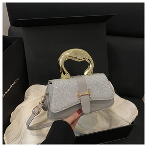 Detailed view of grey sequined handbag with gold metallic handle and H-shaped buckle closure
