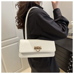 Detail of white baguette bag with woven texture and gold metal clasp on model shoulder