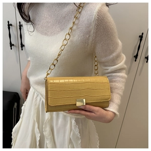 Détail du sac à main jaune avec motif crocodile, chaîne dorée et boucle carrée élégante