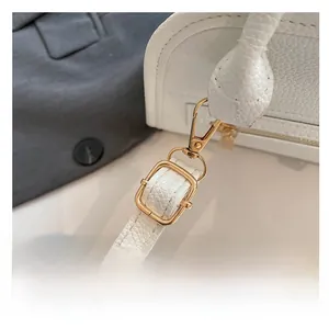 Detail of adjustable shoulder strap on white lychee leather bag with gold hardware