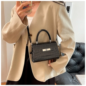 Detail of black crocodile pattern handbag with silver metal buckle and adjustable strap