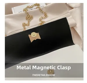 Detail of white leather handbag featuring a golden magnetic clasp and sleek chain strap