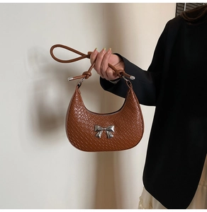 Detailed texture of brown crocodile pattern handbag with silver bow metal hardware