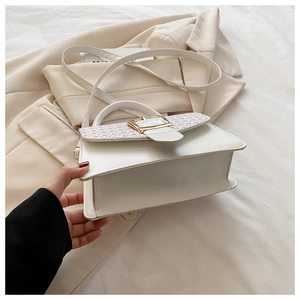 Détail du sac crème avec rabat tissé rose et boucle dorée sur fond de veste de tailleur