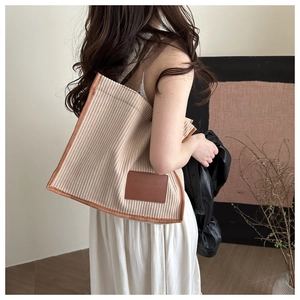 Detail view of striped corduroy tote bag with brown trim and fashion leather label