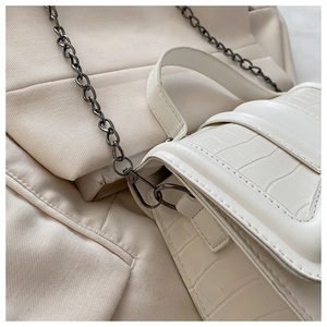 Détail du sac à main crème effet crocodile avec chaîne en métal foncé et rabat élégant