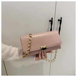 Détail du sac à main rose texture crocodile avec boucle dorée et bandoulière chaîne