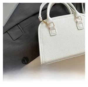 Detailed close-up of white lychee pattern leather Boston bag with light gold hardware