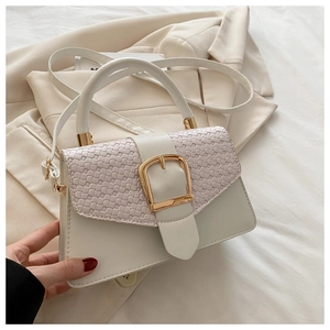 Vue détaillée du sac blanc avec rabat à tissage diagonal et grande boucle dorée chic