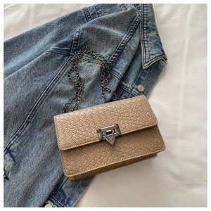 Close-up of beige woven leather crossbody bag with vintage metal buckle on denim jacket