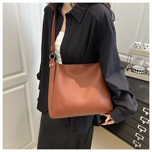 Dettaglio di una borsa a secchiello in pelle marrone con nodo decorativo sulla tracolla