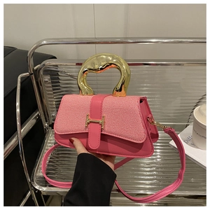 Detail of pink leather handbag with gold H-buckle and stylish metallic handle
