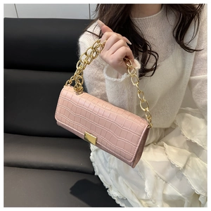 Détail du sac à main rose en cuir de crocodile avec chaîne dorée et boucle carrée en métal