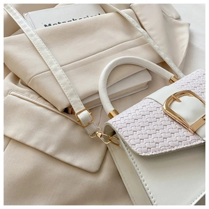 Détail de la texture en cuir tressé blanc et boucle fer à cheval dorée sur le sac