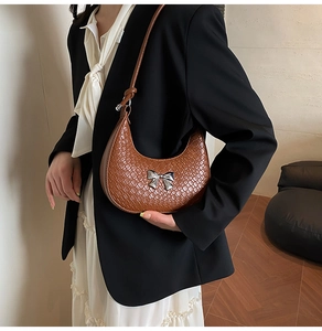 Brown woven hobo bag with a silver metal bow detail shown on a female model