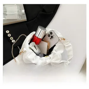 Internal view of a white bow shoulder bag showing storage for phone and cosmetics