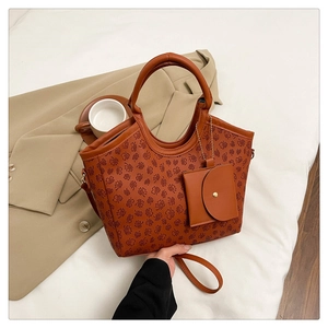 Detailed view of brown tote bag with clover pattern, small pouch and thin strap