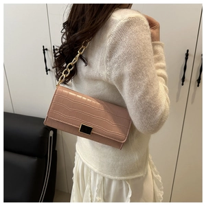 Détail de la texture crocodile rose avec bandoulière chaîne dorée et boucle carrée noire