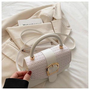 Détail du rabat tissé et de la boucle dorée sur un sac à main blanc minimaliste