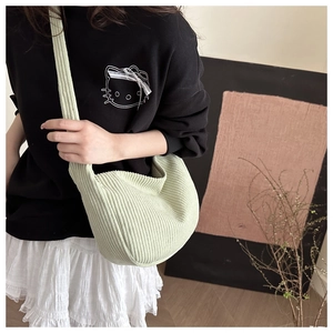 Detailed shot of light green corduroy dumpling bag with a comfortable wide shoulder strap