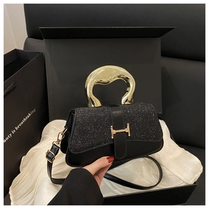 Detail of black sequined handbag featuring a golden H-shaped clasp and creative handle