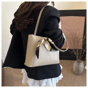 Dettaglio della borsa tote beige con manico in foulard floreale e texture lucida