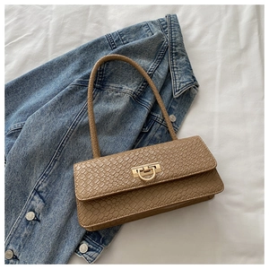 Detailed view of crocodile texture and golden D-ring on brown underarm bag