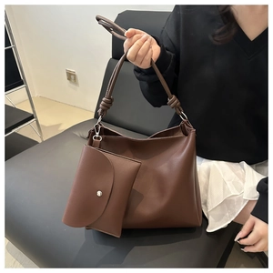 Detail of dark brown leather hobo bag with knotted shoulder strap and attached mini pouch