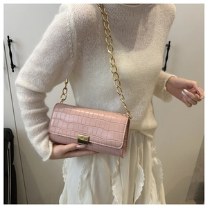 Détail d'un sac baguette rose à motif crocodile avec bandoulière chaîne dorée
