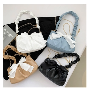 Flat lay of four pleated bow handbags in white, light blue, khaki, and black colors